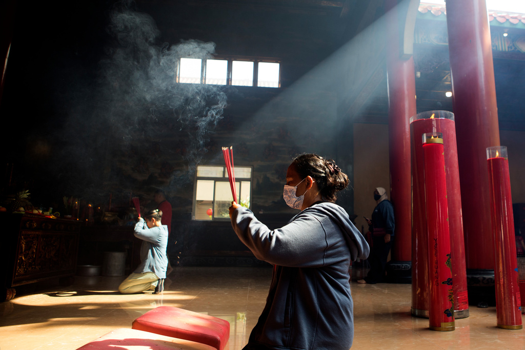 People hold incense sticks as they pray during the celebration of the Lunar New Year of the Horse at Satya Dharma Temple in Denpasar, Indonesia, Tuesday, Feb. 17, 2026. (AP Photo/Firdia Lisnawati)