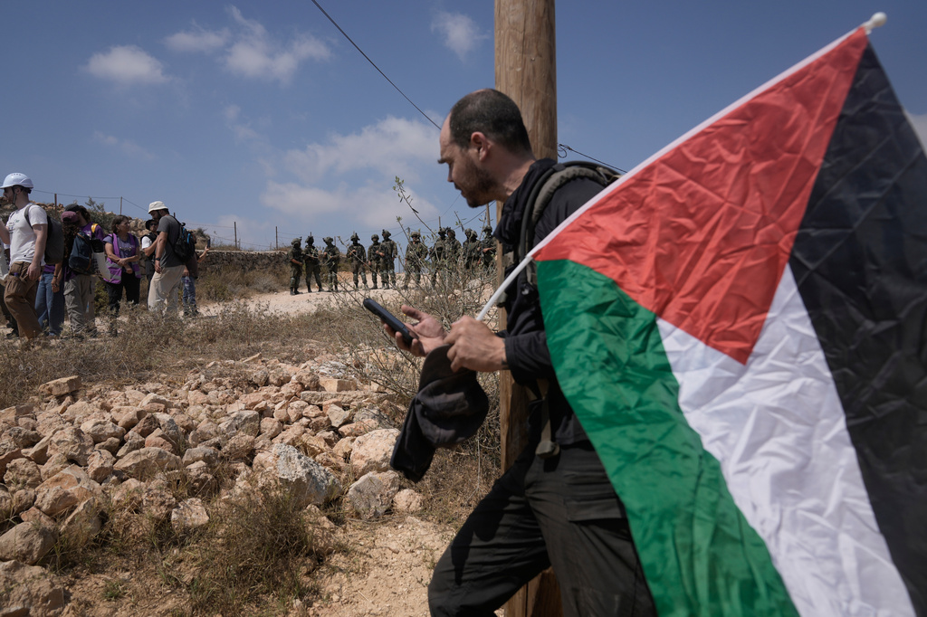 Israeli army soldiers turn back activists who marched with food and water supplies toward the houses of three Palestinian families that have been besieged by Israeli settlers for six days, in the occupied West Bank village of Qusra, south of Nablus, Friday, Aug. 14, 2026. (AP Photo/Majdi Mohammed)