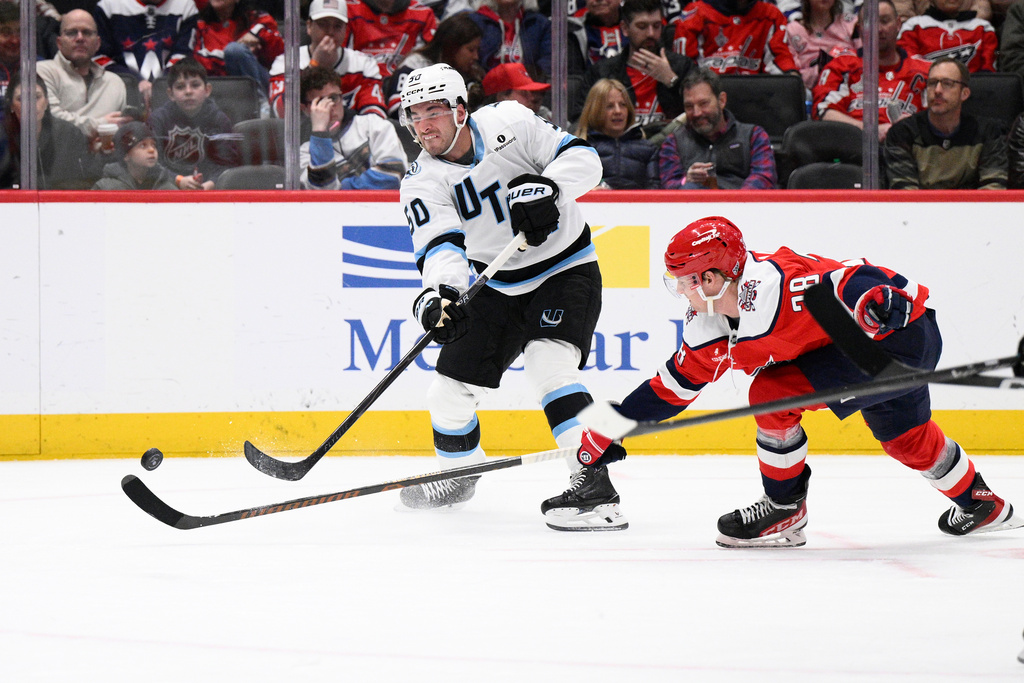 Utah Mammoth defenseman Sean Durzi (50) shoots the puck against Washington Capitals defenseman Rasmus Sandin (38) during the second period of an NHL hockey game, Tuesday, March 3, 2026, in Washington. (AP Photo/Nick Wass)