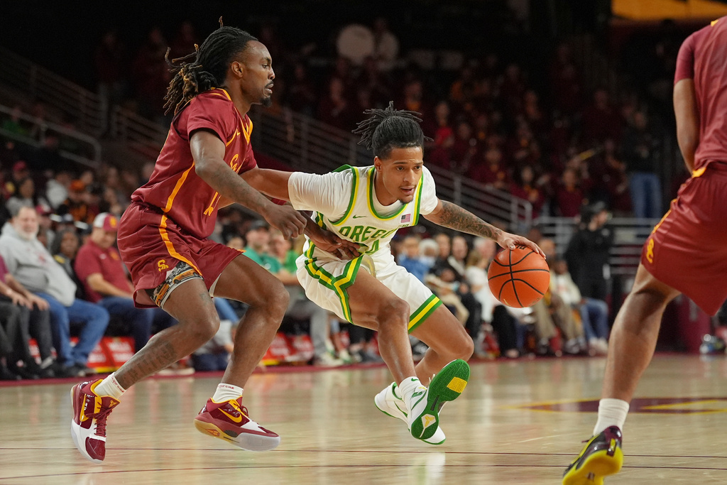 Oregon Jaman Phillips (24) drives as Southern California guard Kam Woods (13) defends during the first half of an NCAA college basketball game Saturday, Feb. 21, 2026, in Los Angeles. (AP Photo/Damian Dovarganes)