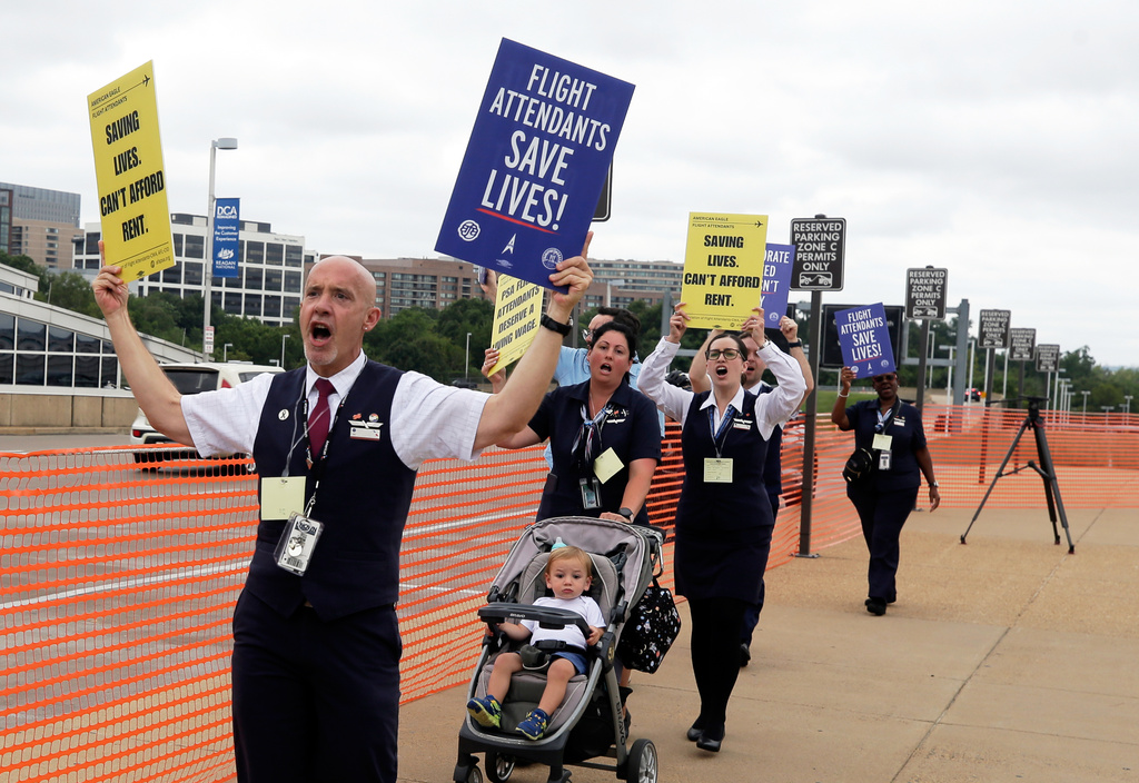 PSA Airlines flight attendants hold placards during a demonstration at Ronald Reagan Washington National Airport, Monday, August 18, 2025, in Washington. (AP Photo/Rahmat Gul)