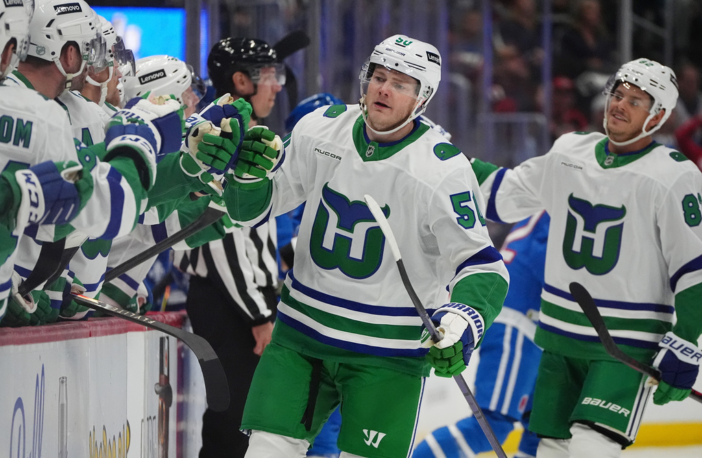 Carolina Hurricanes left wing Eric Robinson is congratulated as he passes the team box after scoring a goal against the Colorado Avalanche in the first period of an NHL hockey game Thursday, Oct. 23, 2025, in Denver. (AP Photo/David Zalubowski)
