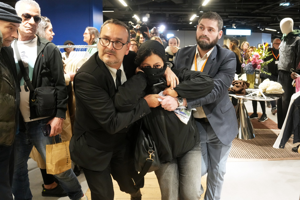 A protester is escorted out of the BHV department store as fast fashion Shein opens its first physical store, Wednesday, Nov. 5, 2025, in Paris. (AP Photo/Thibault Camus)