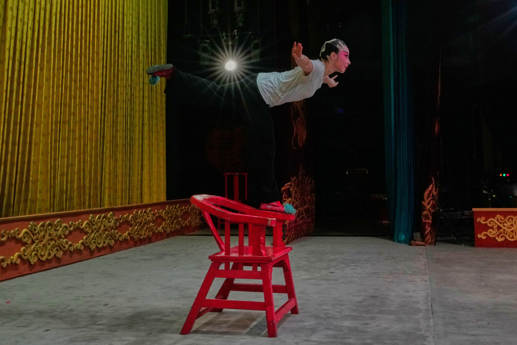 Peking Opera actress Zhang Wanting practices balancing on a chair handle onstage before a performance at Jixiang Theatre in Beijing, China, Sunday, Sept. 7, 2025. (AP Photo/Mahesh Kumar A.)