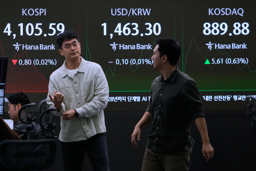Currency traders work near a screen showing the Korea Composite Stock Price Index (KOSPI), top left, and the foreign exchange rate between U.S. dollar and South Korean won, top center, at the foreign exchange dealing room of the Hana Bank headquarters in Seoul, South Korea, Wednesday, Nov. 12, 2025. (AP Photo/Ahn Young-joon)