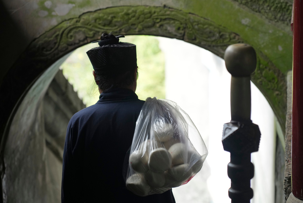 A Taoist priest walks with a bag of buns over his shoulder near the Golden Hall in Wudang Mountains in central China's Hubei Province on Sept. 3, 2026. (AP Photo/Achmad Ibrahim)