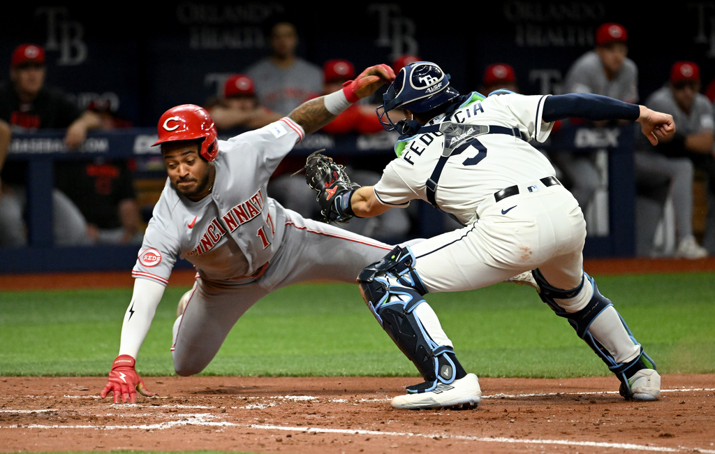Cincinnati Reds' Dane Myers (17) avoids the tag from Tampa Bay Rays catcher Hunter Feduccia (9) as he scores during the sixth inning of a baseball game Tuesday, April 21, 2026, in St. Petersburg, Fla. (AP Photo/Jason Behnken)