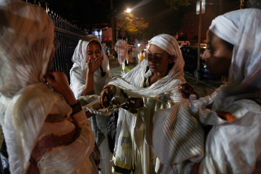A group of women break their fast together outside of Re'ese Adbarat Debre Selam Kidist Mariam Church, an Ethiopian Orthodox Tewahedo church, in Washington, after Easter service, Sunday, April 12, 2026. (AP Photo/Jessie Wardarski)
