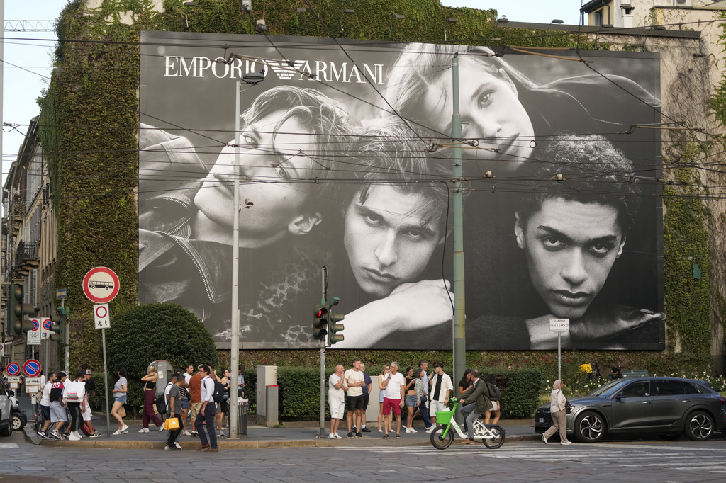 People walk by an advertising for Emporio Armani, the fashion house of designer Giorgio Armani, who died in Milan, Thursday, Sept. 4, 2025. (AP Photo/Luca Bruno)