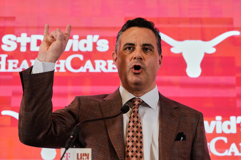 FILE - Texas' coach Sean Miller gives a "Hook'em Horns" sign after he was introduced during an NCAA college basketball news conference in Austin, Texas, March 25, 2025. (AP Photo/Eric Gay, File)
