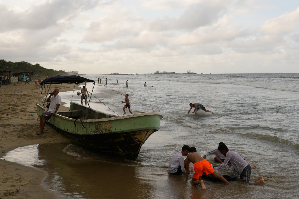 Children play at the beach near El Palito port in Puerto Cabello, Venezuela, Sunday, Dec. 21, 2025. (AP Photo/Matias Delacroix)