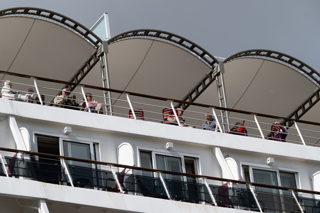 Passengers stand aboard the British cruise ship Ambition, as French authorities have ordered 1,700 passengers and crew to stay on board due to a gastrointestinal illness outbreak, in Bordeaux, southwestern France, Wednesday, May 13, 2026. (AP Photo/Caroline Blumberg)