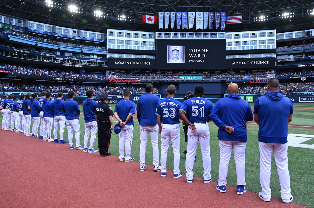 Players and coaches of the Toronto Blue Jays recognize a moment of silence on the announcement of the passing of former Blue Jays pitcher Duane Ward prior to the start of the game against the Chicago White Sox in MLB baseball action in Toronto on Sunday, July 19, 2026. (Jon Blacker/The Canadian Press via AP)