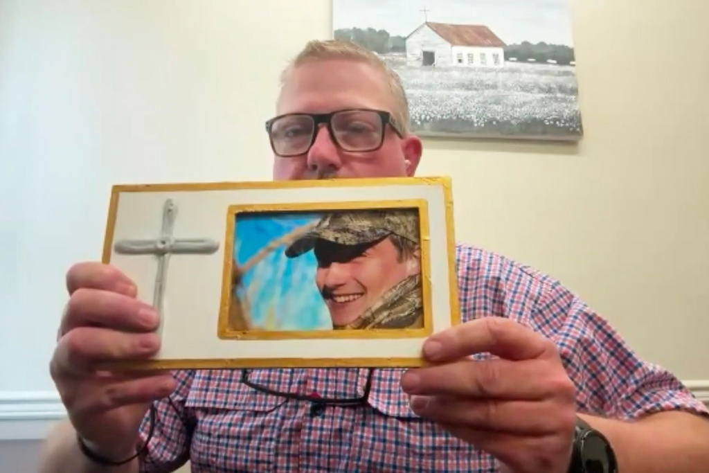 This image taken from video shows Brian Montgomery holding a photo of his son Walker Montgomery while being interviewed by The Associated Press on Wednesday, March 25, 2026, Starkville, Miss. (AP Photo)