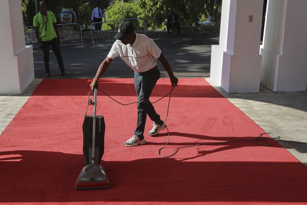 A worker cleans the red carpet for the installation ceremony of Laurent Saint-Cyr, who replaces Fritz Alphonse Jean, for the rotating presidency of the transitional presidential council in Port-au-Prince, Haiti, Thursday, Aug. 7, 2025. (AP Photo/Odelyn Joseph)