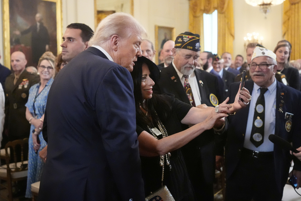 President Donald Trump, left, takes a selfie with an attendee as he departs an event to mark National Purple Heart Day in the East Room of the White House, Thursday, Aug. 7, 2025, in Washington. (AP Photo/Mark Schiefelbein)