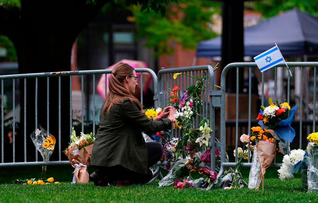 FILE - A woman places a bouquet of flowers at a makeshift memorial for victims of an attack outside of the Boulder County, Colo., courthouse, June 3, 2025, in Boulder, Colo. (AP Photo/David Zalubowski, File)