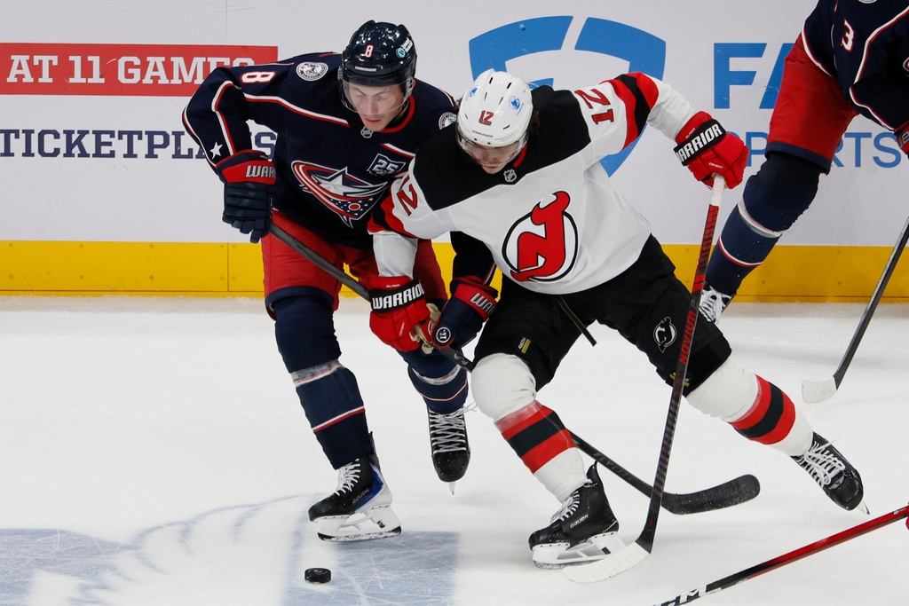 Columbus Blue Jackets' Zach Werenski, left, and New Jersey Devils' Cody Glass (12) fight for the puck during the third period of an NHL hockey game, Monday, Oct. 13, 2025, in Columbus, Ohio. (AP Photo/Jay LaPrete)