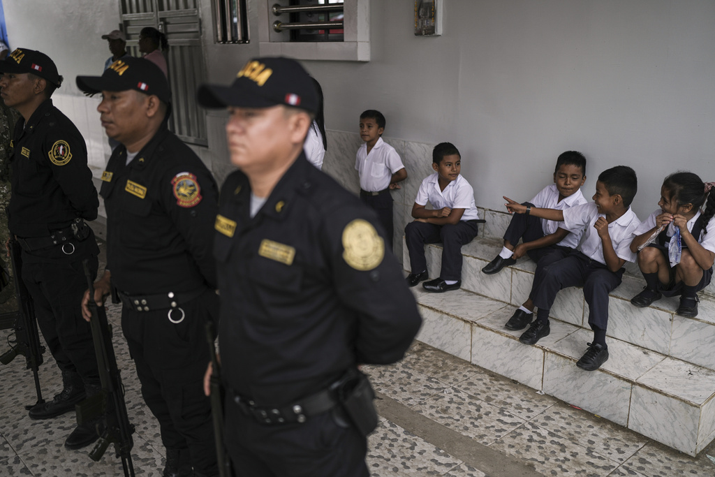 Students sit behind Peruvian police forming ranks to for a flag ceremony in Santa Rosa, Peru, an island on the Amazon River at the center of a territorial dispute with Colombia, Sunday, Aug. 17, 2025. (AP Photo/Ivan Valencia)