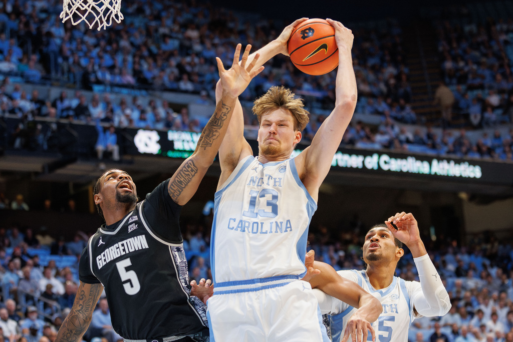 North Carolina's Henri Veesaar (13) grabs a rebound between teammate Jarin Stevenson (15) and Georgetown's KJ Lewis (5) during the first half of an NCAA college basketball game in Chapel Hill, N.C., Sunday, Dec. 7, 2025. (AP Photo/Ben McKeown)