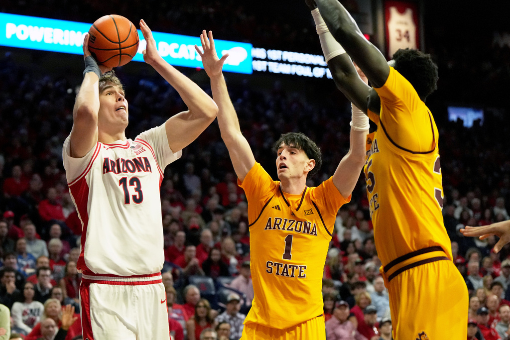 Arizona center Motiejus Krivas (13) shoots over Arizona State forward Santiago Trouet (1) and center Massamba Diop during the first half of an NCAA college basketball game, Wednesday, Jan. 14, 2026, in Tucson, Ariz. (AP Photo/Rick Scuteri)