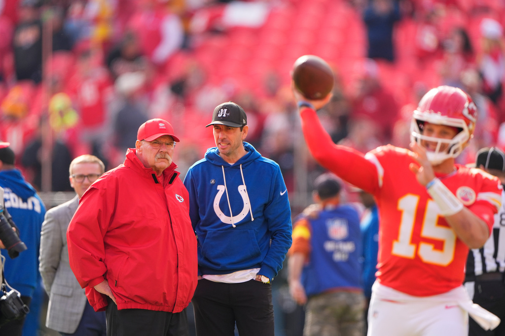 Kansas City Chiefs head coach Andy Reid, left, and Indianapolis Colts head coach Shane Steichen talk as quarterback Patrick Mahomes (15) throws before an NFL football game Sunday, Nov. 23, 2025, in Kansas City, Mo. (AP Photo/Charlie Riedel)