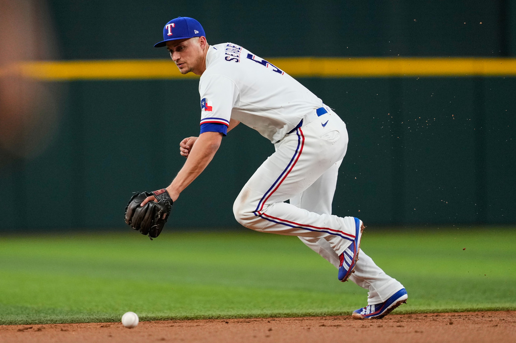 Texas Rangers shortstop Corey Seager is unable to reach a single by Washington Nationals' Jacob Young in the second inning of a baseball game Wednesday, Aug. 19, 2026, in Arlington, Texas. (AP Photo/Tony Gutierrez)