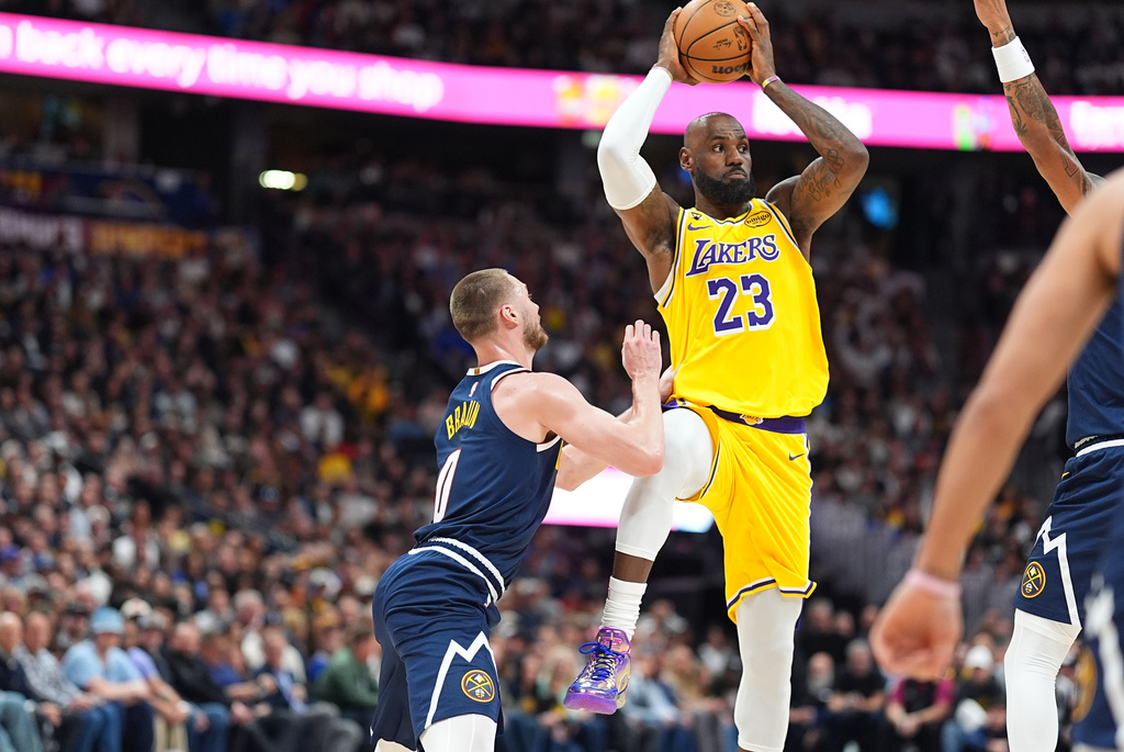 Los Angeles Lakers forward LeBron James, right, passes the ball as Denver Nuggets guard Christian Braun defends in the first half of an NBA basketball game, Thursday, March 5, 2026, in Denver. (AP Photo/David Zalubowski)