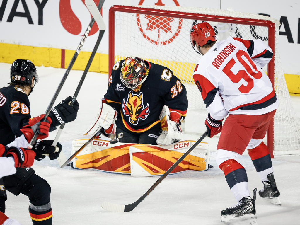 Carolina Hurricanes' Eric Robinson, right, has his shot stopped by Calgary Flames goalie Dustin Wolf during first period NHL hockey action in Calgary on Saturday, March 7, 2026.T (Jeff McIntosh/The Canadian Press via AP)