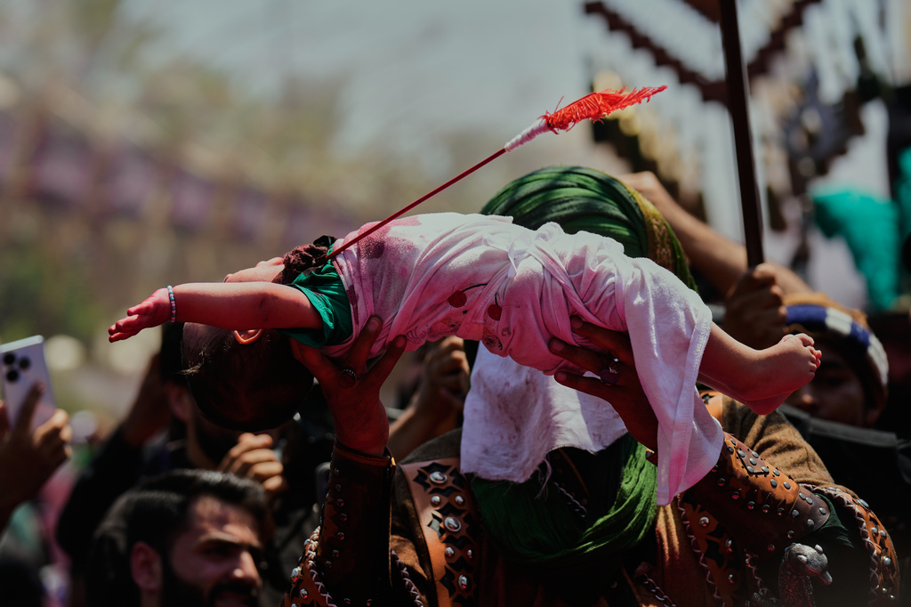 An Iraqi Shiite holds a baby dressed to symbolize the slain 6-month-old son of Imam Hussein, during Ashoura commemorations in Karbala, Iraq, Thursday, June 25, 2026. (AP Photo/Hadi Mizban)
