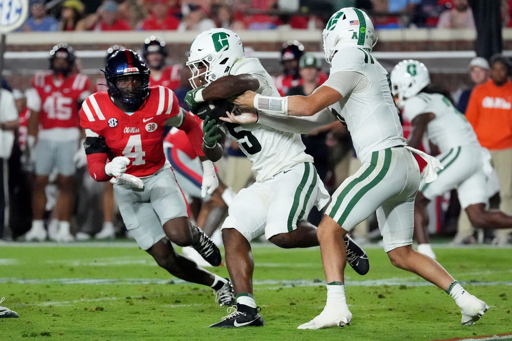 Charlotte running back Khamani Alexander (5) takes a handoff from quarterback Cole Gonzales (9) while pursued by Mississippi linebacker Suntarine Perkins (4) during the first half of an NCAA college football game in Oxford, Miss., Saturday, Sept. 12, 2026. (AP Photo/Rogelio V. Solis)