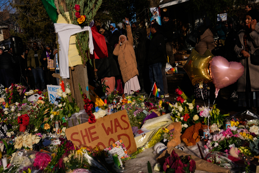 People gather around a makeshift memorial honoring Renee Good, who was fatally shot by an ICE officer, near the site of the shooting in Minneapolis, Friday, Jan. 9, 2026. (AP Photo/John Locher)