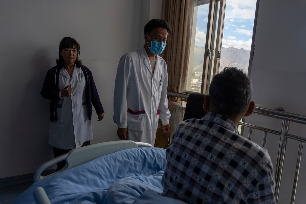 Ciren Deji, a neurologist, left and Gama, a physician, visit a Tibetan man, right, in a ward for traditional Tibetan therapy at the Xizang Autonomous Region Hospital of Tibetan Medicine in Lhasa, in western China's Tibet Autonomous Region on Wednesday, July 22, 2026 as seen during a government organized visit for foreign journalists. (AP Photo/Ng Han Guan)