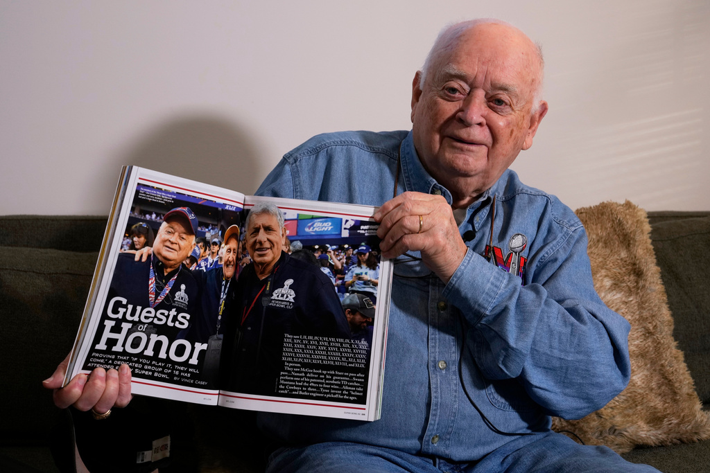 Don Crisman holds a copy of the official program for Super Bowl 50, which featured a story on a small group of fans, including Crisman, who had attended every championship game, Friday, Jan. 23, 2026, in Kennebunk, Maine. (AP Photo/Robert F. Bukaty)