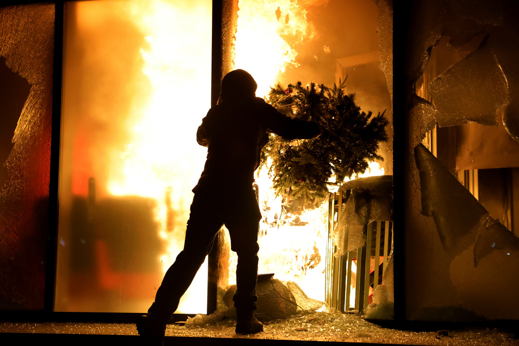 A hooded protester vandalizes the Justice Ministry during clashes in Tirana, Albania, Wednesday, Oct. 14, 2026, as students joined the Flamingo anti-government movement. (AP Photo/Hameraldi Agolli)