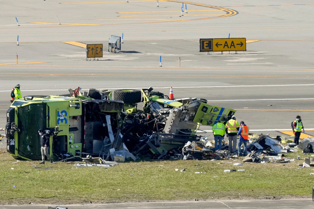 Officials inspect the wreckage of a Port Authority fire truck, Tuesday, March 24, 2026, just off the runway where it had collided with an Air Canada Express jet, Sunday night at LaGuardia Airport in New York. (AP Photo/Yuki Iwamura)