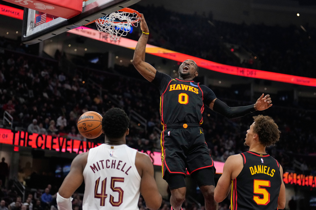 Atlanta Hawks forward Jonathan Kuminga (0) dunks in front of Cleveland Cavaliers guard Donovan Mitchell (45) and teammate Dyson Daniels (5) in the second half of an NBA basketball game in Cleveland, Wednesday, April 8, 2026. (AP Photo/Sue Ogrocki)
