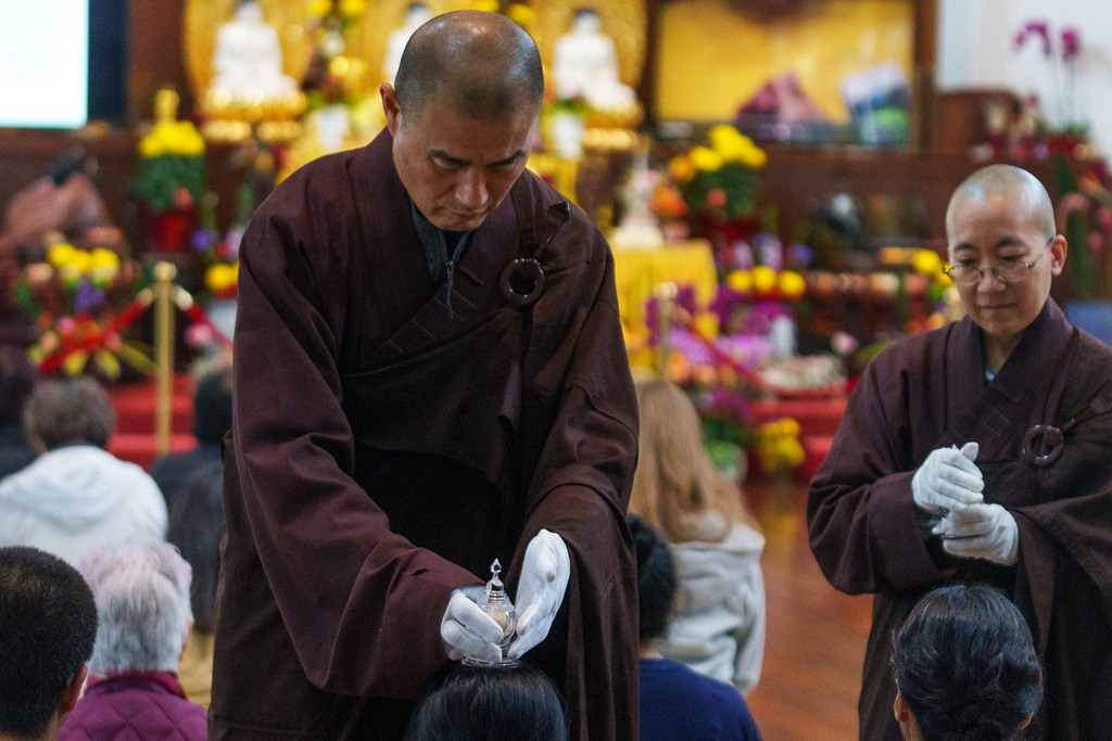 Buddhist resident monks perform a blessing to devotees and visitors at Wei Mountain Temple, in Rosemead, Calif., Saturday, Feb. 17, 2024. (AP Photo/Damian Dovarganes)