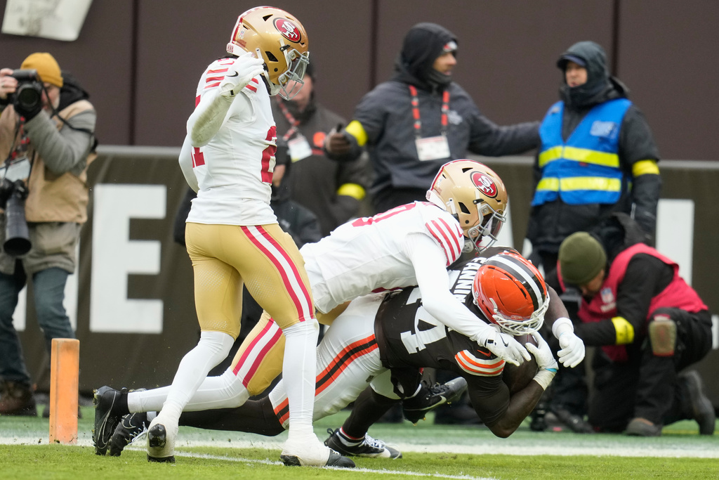 Cleveland Browns tight end Harold Fannin Jr., bottom, scores under San Francisco 49ers cornerback Renardo Green, middle, and safety Ji'Ayir Brown, left, during the first half of an NFL football game, Sunday, Nov. 30, 2025, in Cleveland. (AP Photo/Sue Ogrocki)