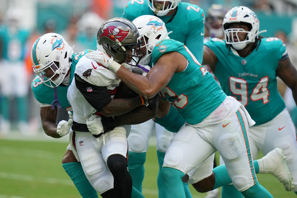 Miami Dolphins defensive tackle Zeek Biggers, front right, and cornerback Jason Marshall Jr. (33) tackle Tampa Bay Buccaneers running back Bucky Irving, second from left, during the first half of an NFL football game Sunday, Dec. 28, 2025, in Miami Gardens, Fla. (AP Photo/Lynne Sladky)