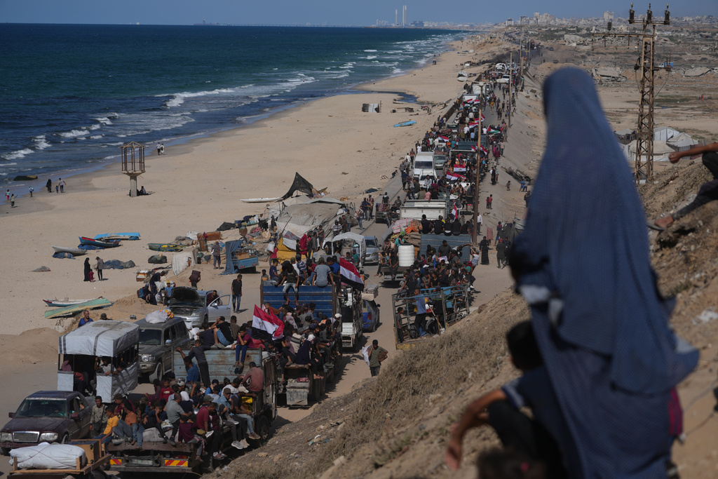 Displaced Palestinians ride on trucks loaded with belongings and wave Egyptian and Palestinian flags as they travel along the coastal road near Wadi Gaza in the central Gaza Strip, moving toward Gaza city, Saturday, Oct. 11, 2025, after Israel and Hamas agreed to a pause in their war and the release of the remaining hostages. (AP Photo/Jehad Alshrafi)