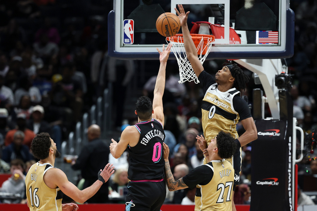 Miami Heat forward Simone Fontecchio, center, goes to the basket and attempts a layup but has his shot blocked by Washington Wizards guard Bilal Coulibaly, top right, while being fouled by Wizards guard Will Riley (27) during the first half of an NBA basketball game, Friday, April 10, 2026, in Washington. (AP Photo/Terrance Williams)