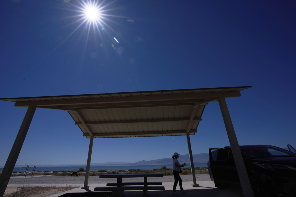 A woman packs up after resting in a shaded area alongside the Salton Sea as a record-breaking winter heat wave continues across the Southwest, Thursday, March 19, 2026, near North Shore, Calif. (AP Photo/Gregory Bull)