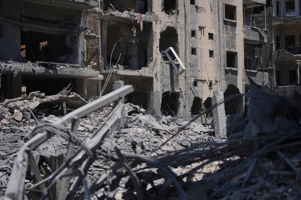 A resident throws debris from an apartment in a building damaged in Israeli strikes in the southern port city of Tyre, Lebanon, Thursday, June 18, 2026. (AP Photo/Hassan Ammar)