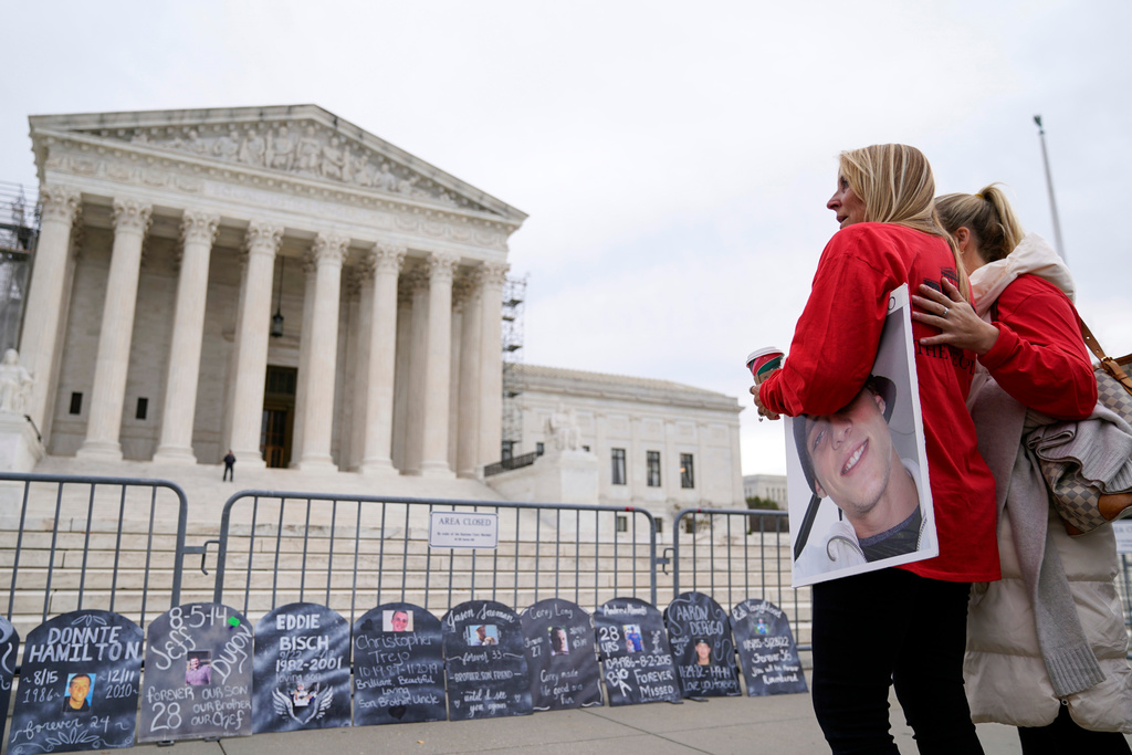 FILE - Jen Trejo holds a photo of her son Christopher as she is comforted outside the Supreme Court Dec. 4, 2023, in Washington. (AP Photo/Stephanie Scarbrough, File)