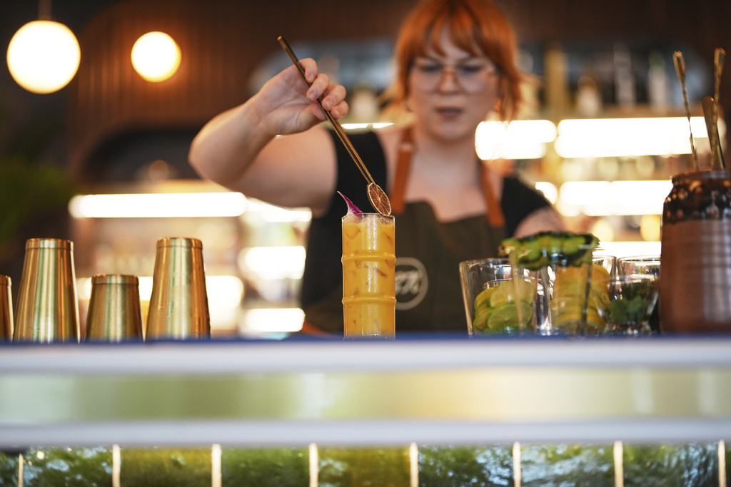 Bartender Shelby Campos adorns the top of a non-alcoholic beverage - or mocktail - with fruit and a flower at the non-alcoholic Good News Bar, Monday, Aug. 25, 2025, in San Diego. (AP Photo/Gregory Bull)