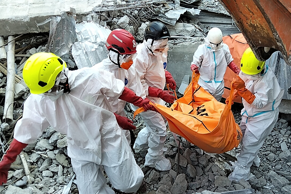 In this photo released by the Indonesian National Search and Rescue Agency (BASARNAS) on Monday, October. 6, 2025, rescuers remove the body of a victim from the rubble of a collapsed building at an Islamic boarding school in Sidoarjo, East Java, Indonesia.(BASARNAS via AP)