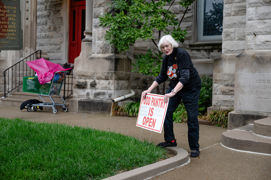 Margaret Dickinson announces the opening of food pantry service with the placement of a sign at Calvary Episcopal Church on Thursday, Oct. 30, 2025, in Louisville, Ky. (AP Photo/Jon Cherry)