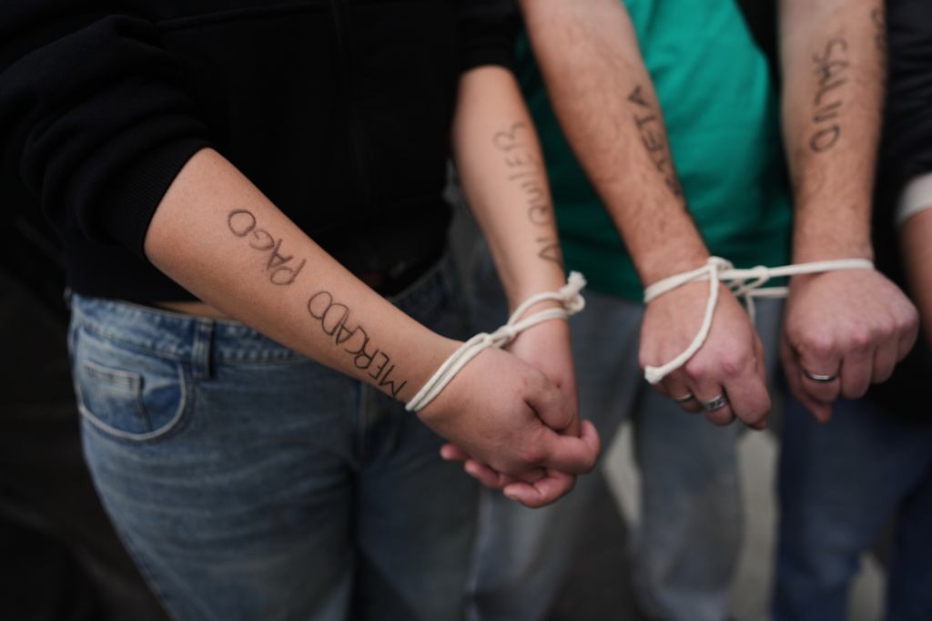 Demonstrators protest with their hands tied outside the Economy Ministry, demanding government action over a household debt crisis, in Buenos Aires, Argentina, Thursday, Aug. 20, 2026. (AP Photo/Victor R. Caivano, File)