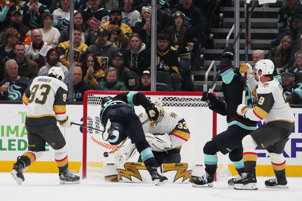 Seattle Kraken left wing Jared McCann, second from left, scores the game-winning goal against Vegas Golden Knights goaltender Adin Hill (33) as right wing Mitch Marner (93) and center Jack Eichel (9) look on during overtime of an NHL hockey game Saturday, Oct. 11, 2025, in Seattle. (AP Photo/Lindsey Wasson)